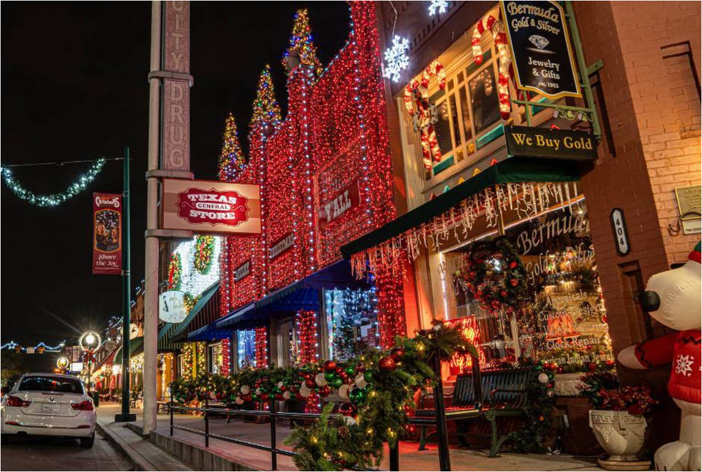 Historic Main Street Grapevine storefronts covered in red, green, and white Christmas lights