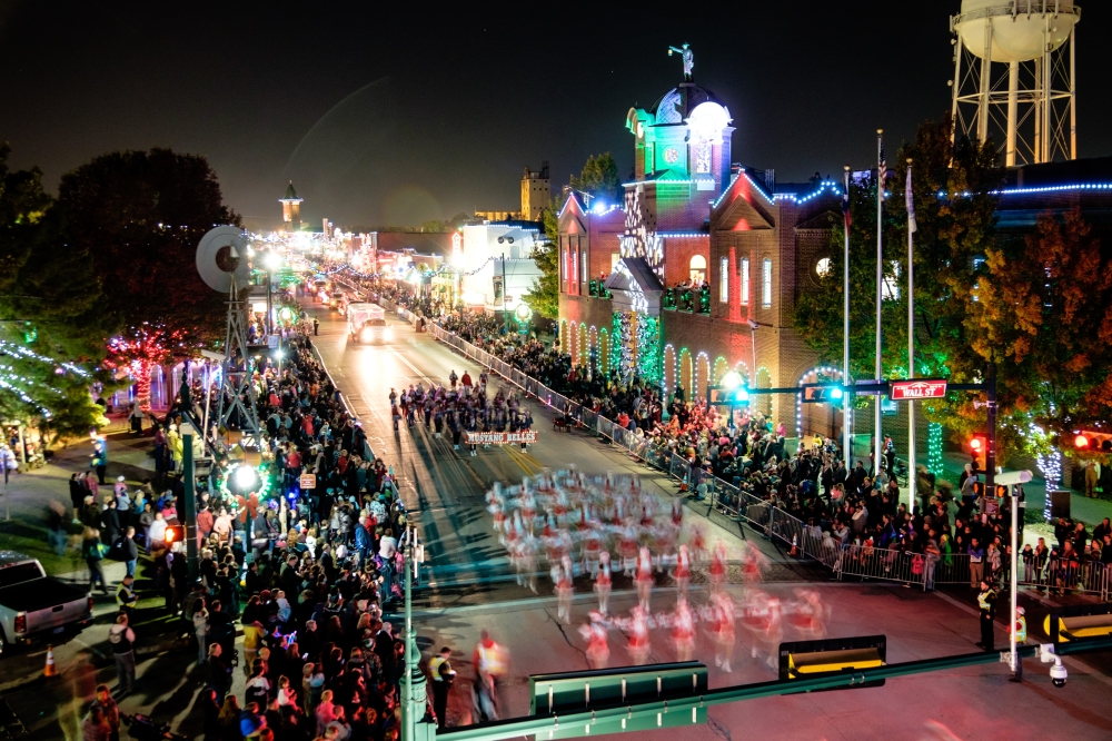 Christmas parade traveling down Historic Main Street in Grapevine past decorated buildings and crowds