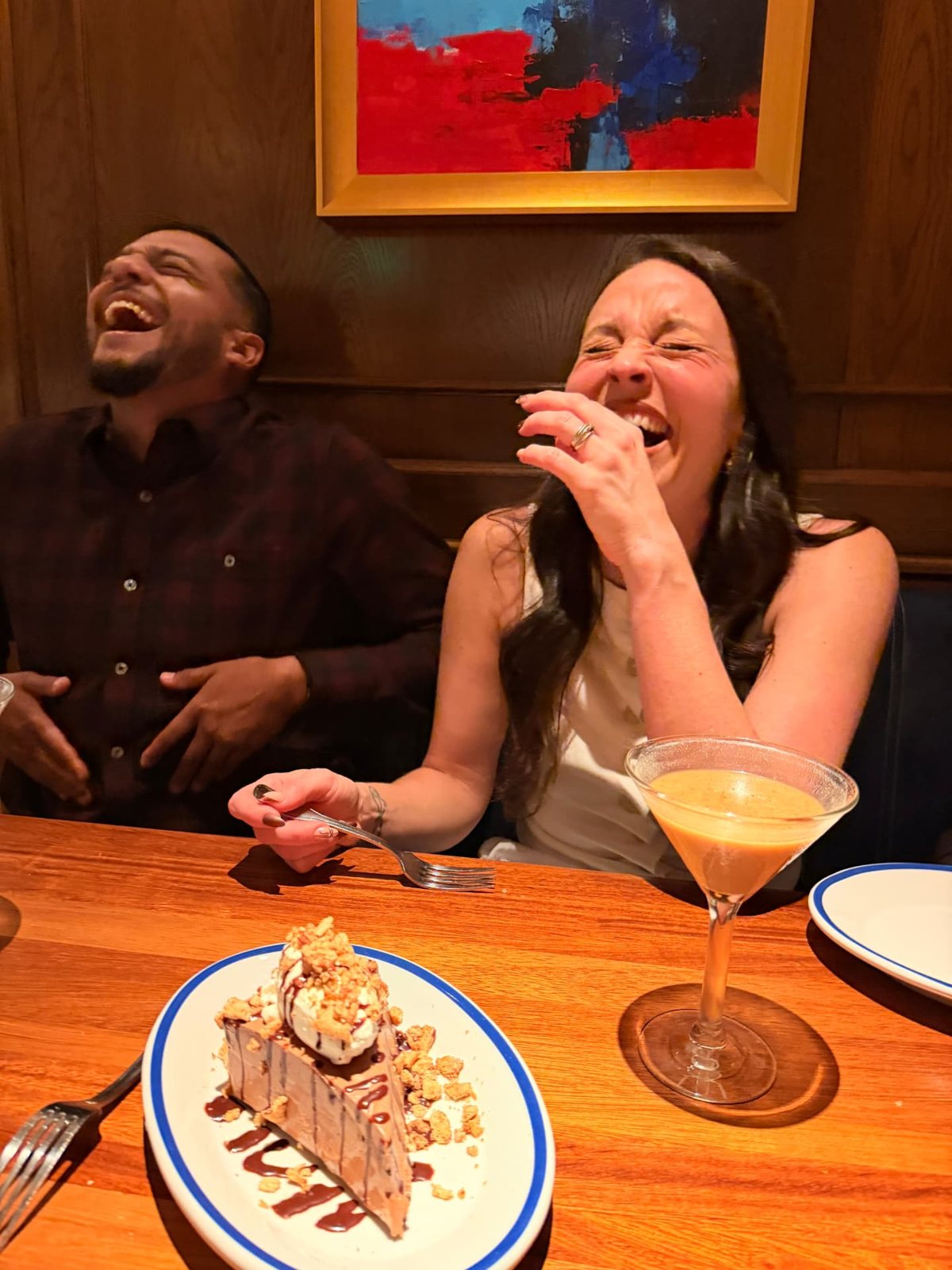 Alyssa and Hector laughing at the table with a chocolate dessert and an espresso martini