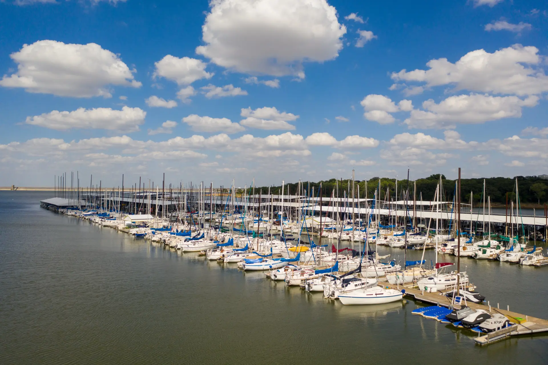 Sailboats docked in rows at Scott's Landing Marina on Grapevine Lake beneath a bright blue sky